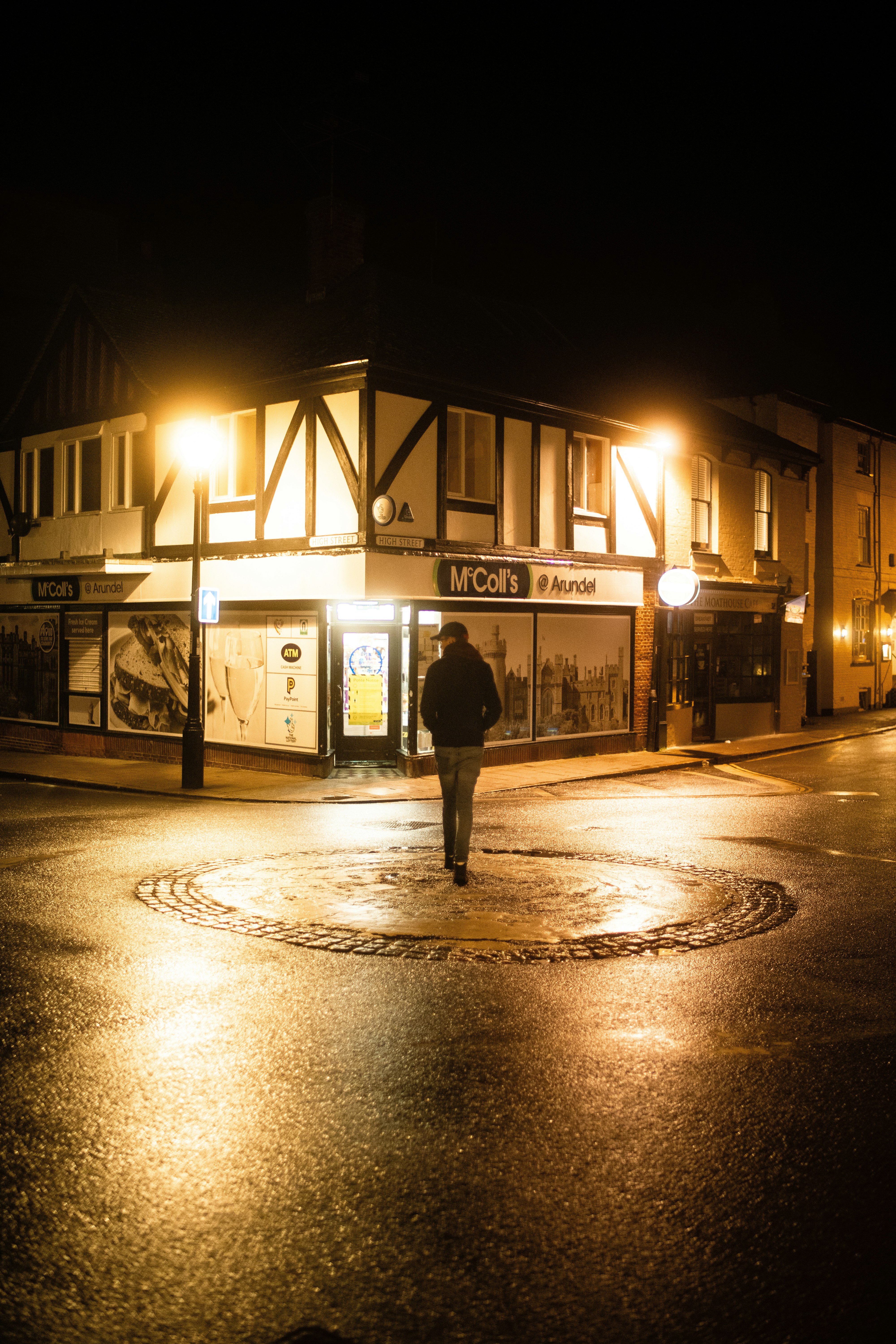 man in black jacket standing on pedestrian lane during night time